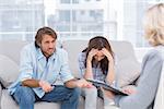 Young couple sit on the couch of the therapist and the woman is crying