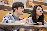 Students sitting in a lecture hall while studying and listening to the teacher