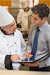 Chef and waiter having a discussion in the kitchen