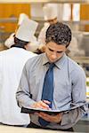 Waiter looking at folder in kitchen