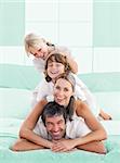 Smiling family piled on top of dad on the bed