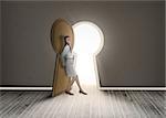 Businesswoman leaning against keyhole shaped doorway in dark grey room