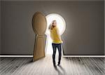 Woman walking towards keyhole shaped doorway with light ikn dark grey room