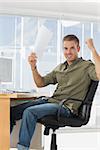 Cheerful creative business employee raising arms in a modern office