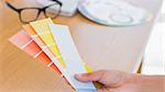 Hand holding colour charts over a desk