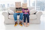 Silly employees with arms folded wearing boxes on their heads with smiley faces on a couch