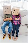 Silly employees wearing boxes on their heads with smiley faces on a couch