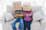 Funny employees wearing boxes on their heads with smiley faces on a couch