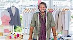 Fashion designer leaning on his desk and smiling to the camera