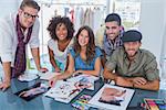 Young designers smiling at camera and working at desk