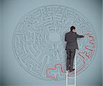 Businessman on ladder drawing red line to solve a maze on grey wall
