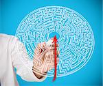 Businessman drawing red line to centre of maze on blue background