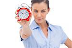 Businesswoman holding alarm clock and looking at the camera