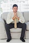 Serious businessman thinking with hands together on sofa