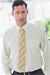 Serious businessman with hands in pocket in office