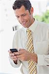 Happy businessman using his phone in office