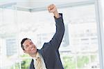 Cheerful businessman raising up his hand in office