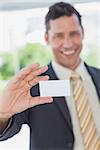Happy businessman showing a white business card in office