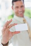 Happy businessman presenting white business card in office