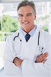 Smiling doctor standing with arms crossed in a modern office