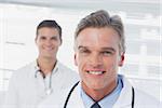 Smiling doctor standing in front of his colleague in a bright office