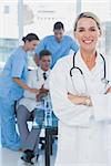 Pretty doctor with arms folded standing in front of medical team