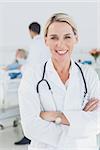 Smiling doctor with arms crossed in front of a patient and a doctor