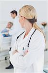 Doctor with arms crossed standing in front of a patient and a doctor