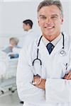 Attractive doctor with arms crossed while doctor taking care of a patient