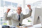 Businessman cheering in his office at his desk