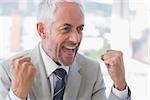 Succesful businessman cheering and clenching fists