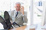 Happy businessman giving ok sign with feet up on his desk