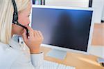 Businesswoman with headset looking at blank computer screen at desk