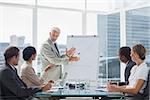 Businessman in front of a growing chart during a meeting with concentrated colleagues