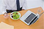 Overhead of a businessman eating a salad on his desk during the lunch time