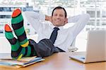 Smiling businessman relaxing with feet over a pile of documents on his desk