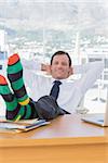 Cheerful businessman relaxing with feet over a pile of documents on his desk
