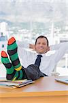 Happy businessman relaxing with feet over a pile of documents on his desk