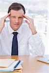 Stressed businessman holding his head in his office