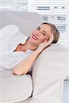 Cheerful businesswoman lying on sofa in office