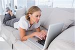 Businesswoman lying on couch and using laptop in the office