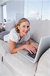 Relaxed businesswoman using her laptop and lying on couch