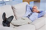 Businessman lying on sofa with his feet up in the office