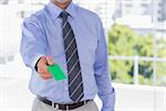 Businessman offering green business card in his office