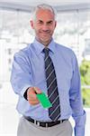 Happy businessman giving green business card in his office