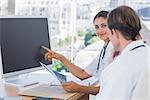 Doctor showing the screen of a computer to a colleague while they are working together