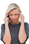 Woman with headache touching her forehead and looking at camera on white background