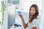 Cheerful brunette designer purchasing online with her credit card
