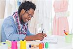 Attractive fashion designer sitting at his desk drawing in a creative office