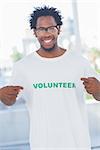 Cheerful man pointing to his volunteer tshirt in a modern office
